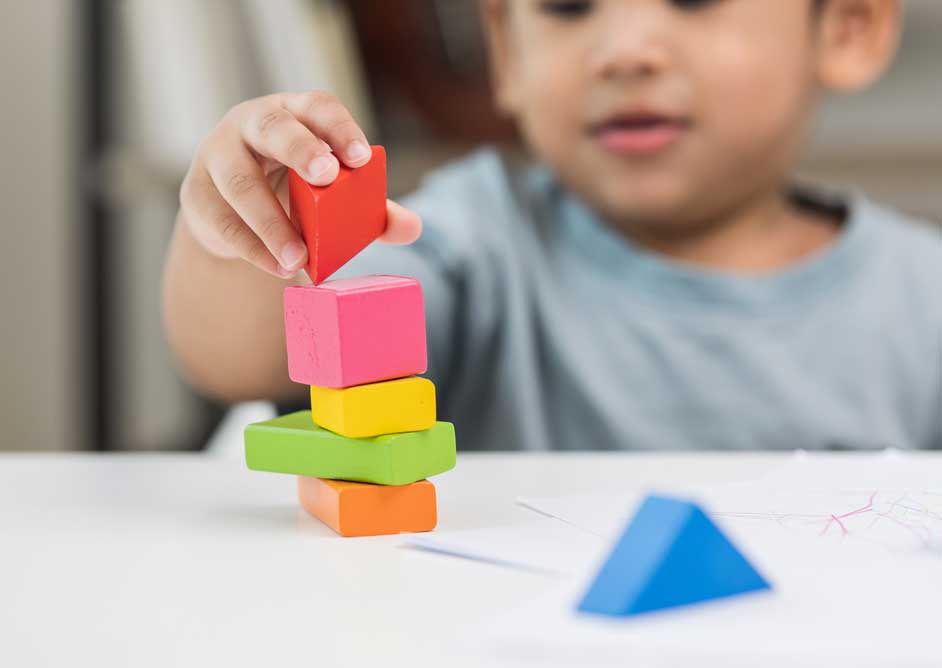 child stacking colourful blocks on top of each other