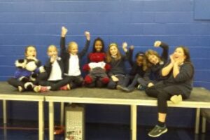 Group of young school kids happily taking a photo together sitting on a table